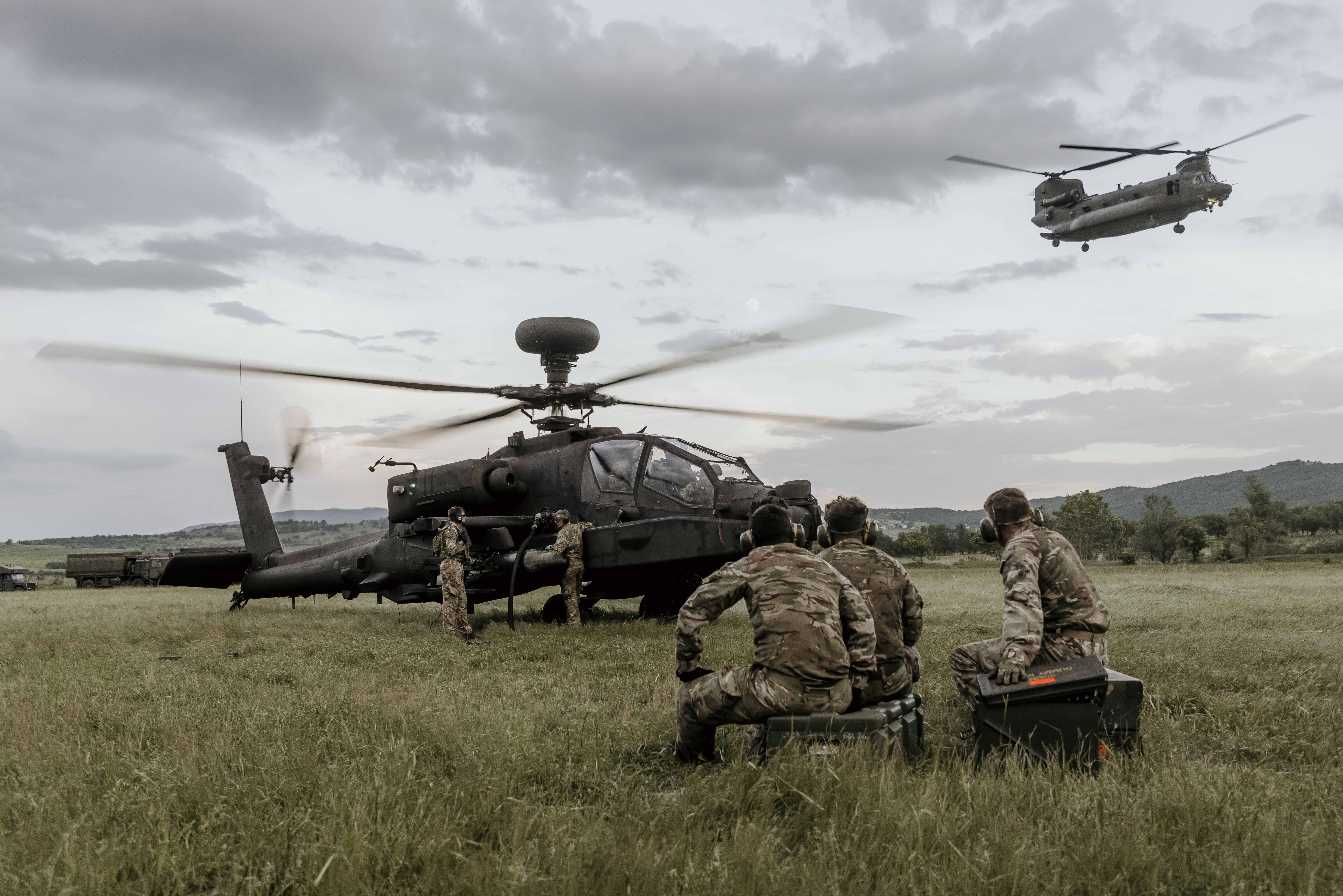 Helicopters and personnel on the ground. One flies by.